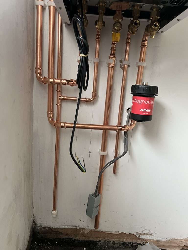 Isolation valves, copper pipework and magnetic system filter beneath a gas boiler
