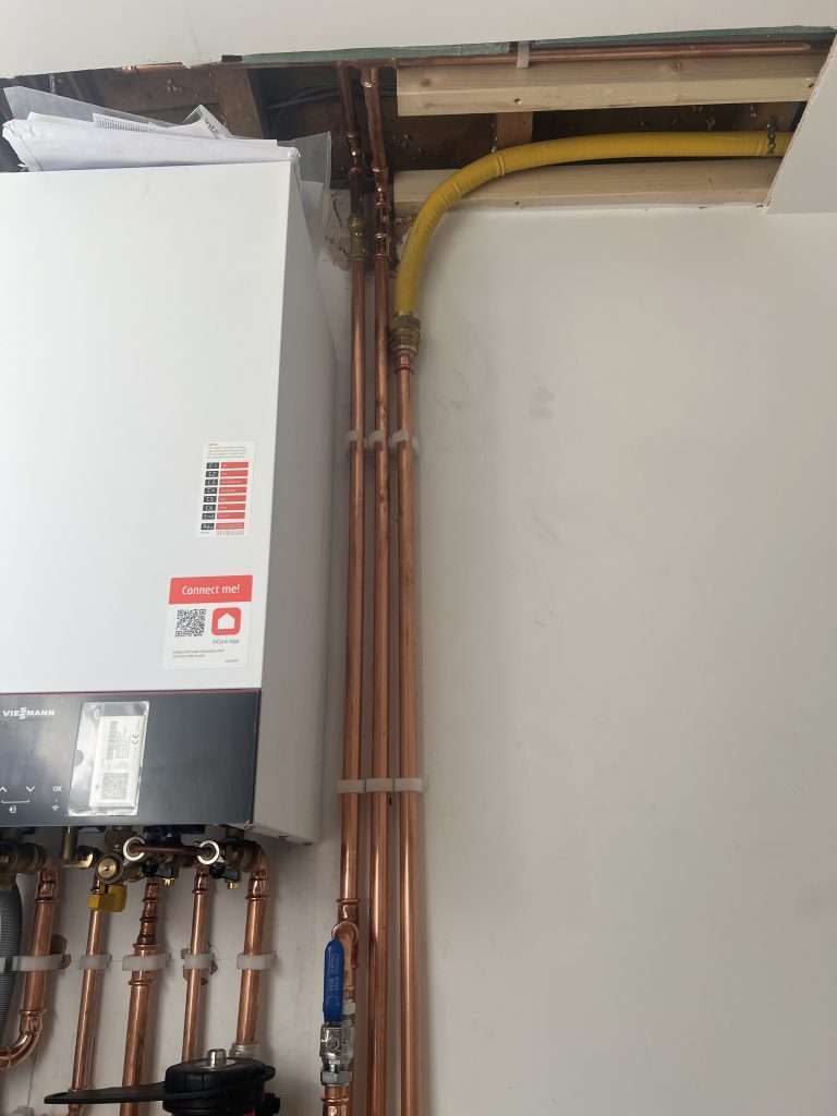 Wall-hung Viessmann gas boiler with yellow gas supply pipe and copper pipework